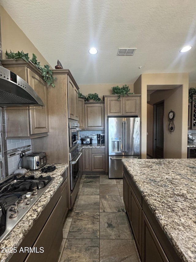 kitchen featuring visible vents, appliances with stainless steel finishes, tasteful backsplash, light stone counters, and recessed lighting