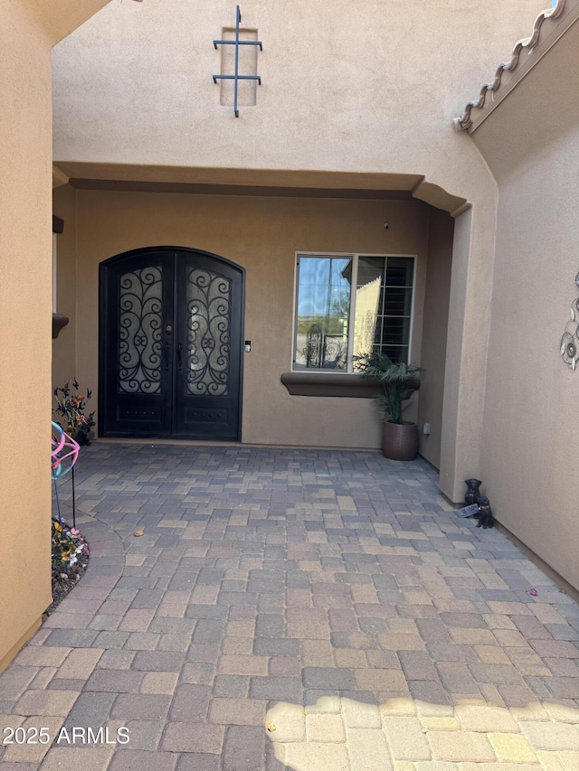 entrance to property featuring stucco siding and french doors