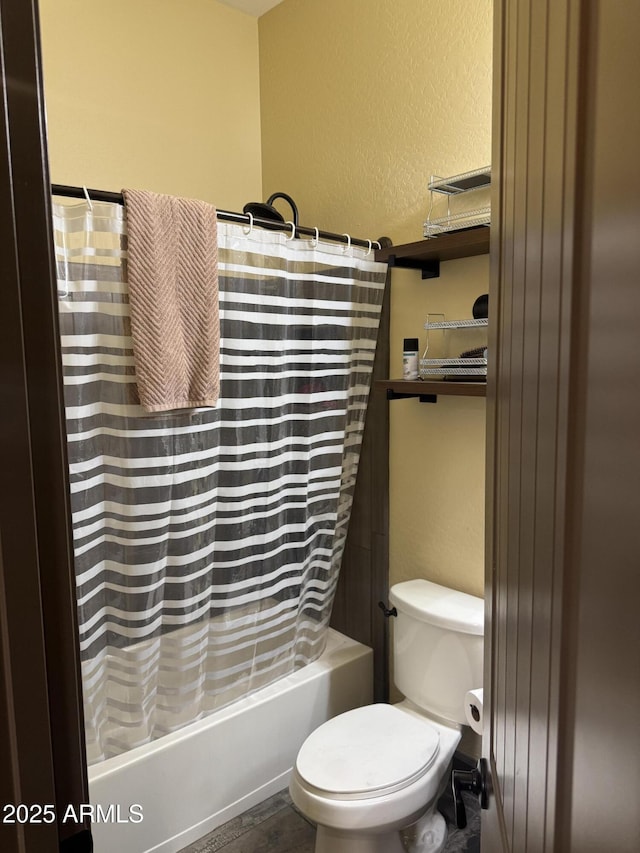 bathroom featuring shower / bath combo with shower curtain, a textured wall, and toilet