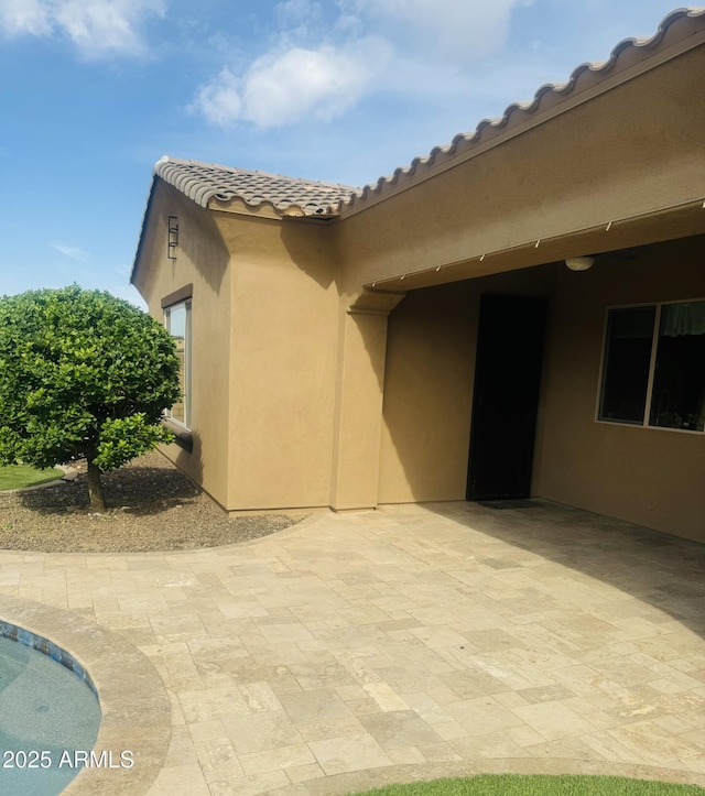 exterior space with a tiled roof, a patio area, and stucco siding