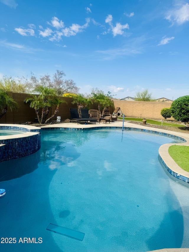 view of pool with a fenced backyard and a pool with connected hot tub
