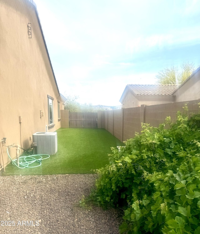 view of yard with central air condition unit and a fenced backyard