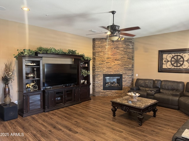 living area with ceiling fan, a fireplace, wood finished floors, and visible vents