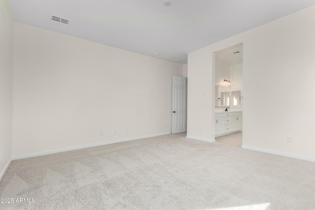 unfurnished bedroom with ensuite bathroom and light colored carpet