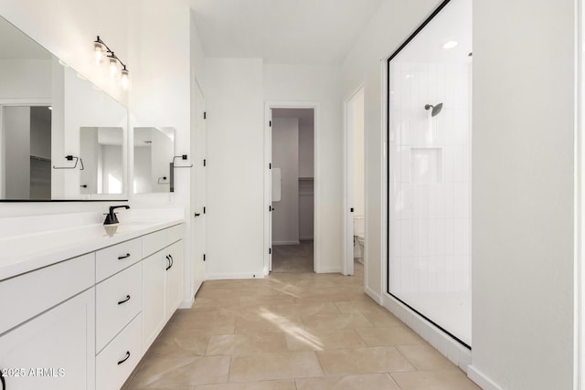 bathroom with tile patterned flooring, a tile shower, vanity, and toilet