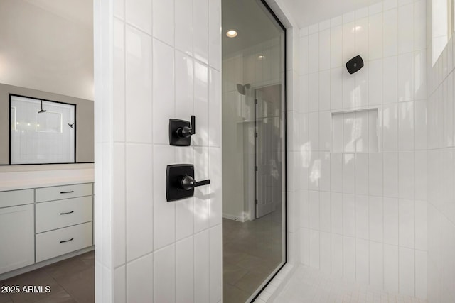 bathroom featuring a tile shower, tile patterned flooring, vanity, and tile walls