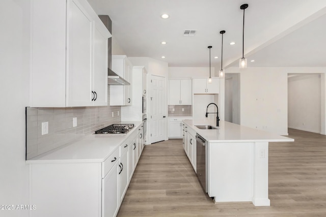 kitchen with decorative light fixtures, an island with sink, white cabinetry, appliances with stainless steel finishes, and sink