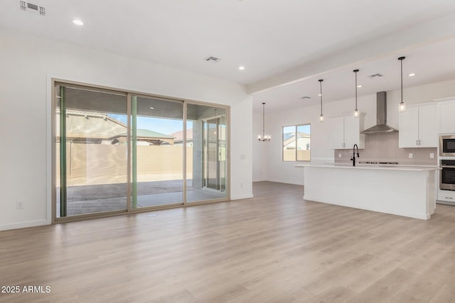 unfurnished living room featuring an inviting chandelier, light hardwood / wood-style floors, and sink