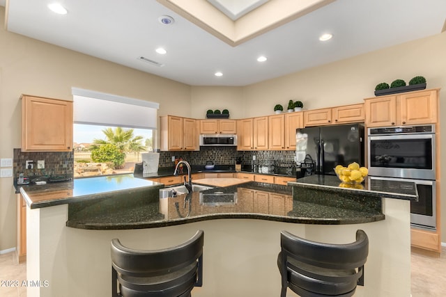 kitchen featuring black appliances, a breakfast bar, and an island with sink