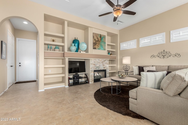 living room with built in shelves, ceiling fan, and a fireplace