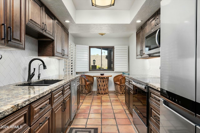 kitchen with appliances with stainless steel finishes, dark brown cabinetry, light stone counters, and sink