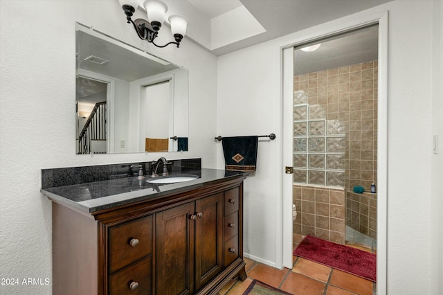 bathroom featuring tile patterned flooring, vanity, tiled shower, and toilet