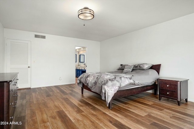 bedroom featuring ensuite bath and wood-type flooring