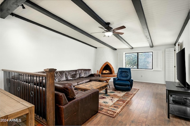 living room with hardwood / wood-style floors, ceiling fan, a large fireplace, and beamed ceiling