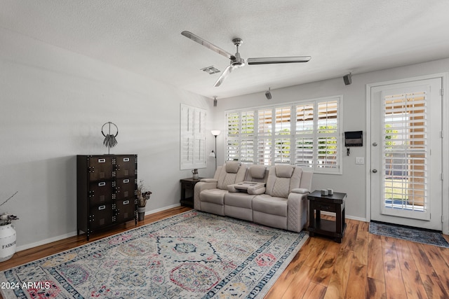 living room with a textured ceiling, hardwood / wood-style flooring, and ceiling fan