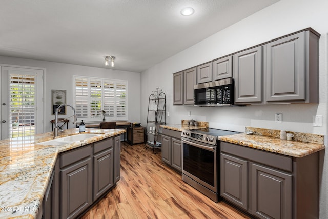 kitchen featuring gray cabinetry, light stone countertops, sink, light hardwood / wood-style floors, and appliances with stainless steel finishes