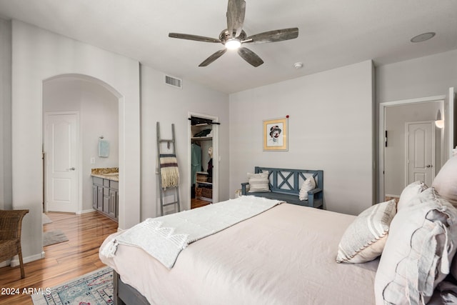 bedroom featuring ensuite bathroom, light hardwood / wood-style flooring, a closet, and ceiling fan