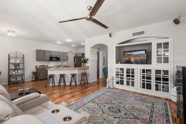 living room featuring dark hardwood / wood-style floors, ceiling fan, and sink