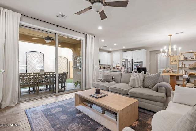 living room with ceiling fan with notable chandelier, light wood-type flooring, visible vents, and recessed lighting