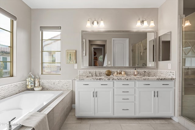 bathroom featuring a stall shower, tile patterned flooring, a garden tub, and a sink