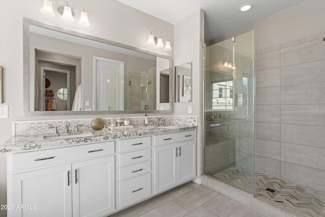 full bath featuring double vanity, a stall shower, a sink, and tile patterned floors