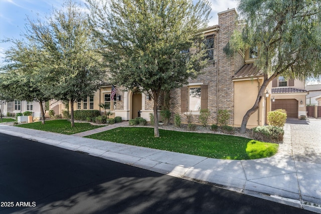 obstructed view of property featuring brick siding, a chimney, stucco siding, a front yard, and driveway