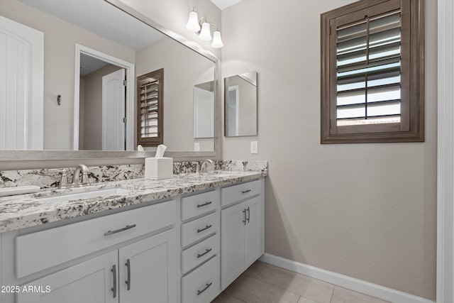 bathroom featuring double vanity, baseboards, a sink, and tile patterned floors