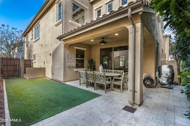 back of house featuring outdoor dining space, a patio area, fence, and stucco siding