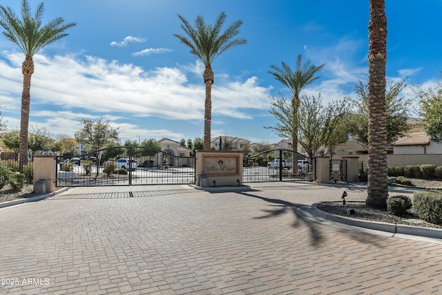 view of street featuring a gate, a gated entry, and curbs