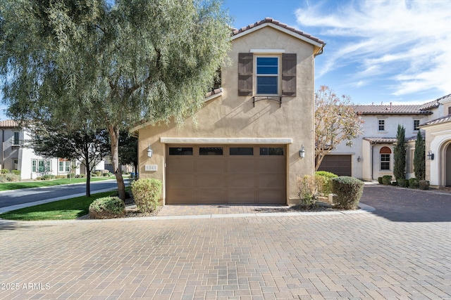 mediterranean / spanish-style home featuring a tiled roof, decorative driveway, and stucco siding