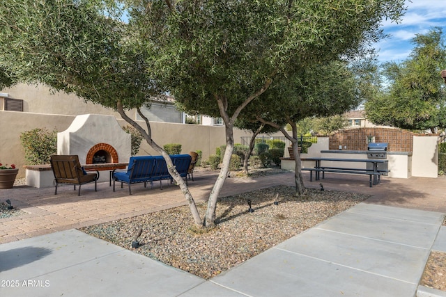 exterior space with a patio, an outdoor kitchen, an outdoor fireplace, and fence