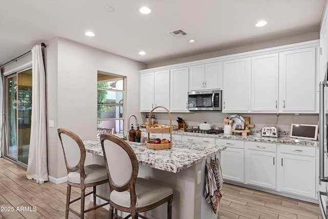 kitchen with white cabinets, appliances with stainless steel finishes, visible vents, and wood tiled floor