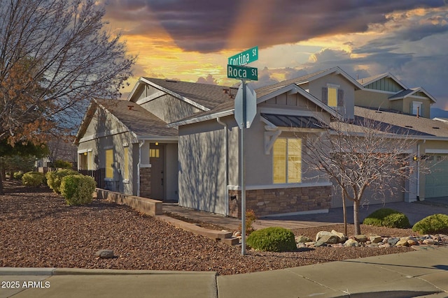 view of front of home featuring a garage, stone siding, and driveway