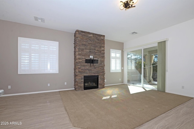 unfurnished living room featuring visible vents, a stone fireplace, and baseboards