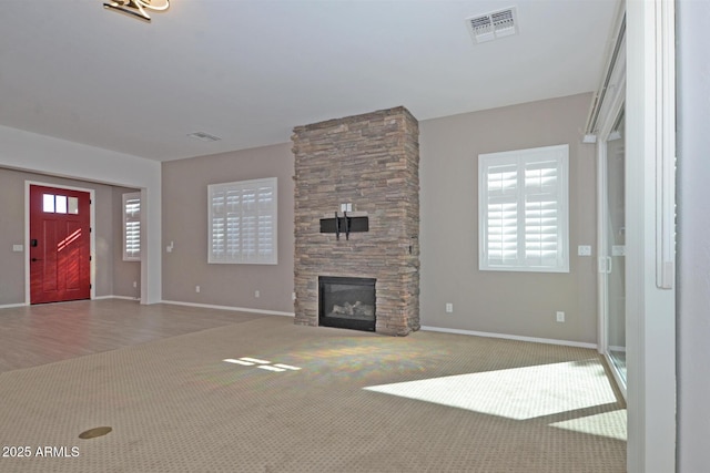 unfurnished living room featuring carpet floors, a healthy amount of sunlight, visible vents, and a fireplace