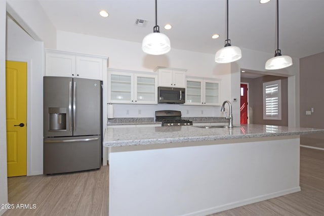 kitchen featuring stainless steel appliances, light wood-style floors, white cabinetry, and a sink