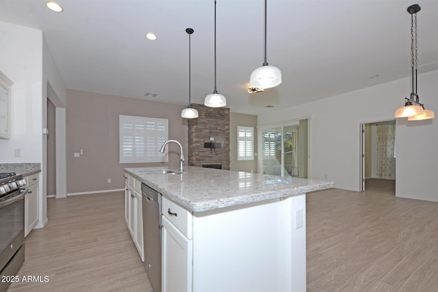 kitchen featuring stainless steel appliances, light wood-type flooring, a sink, and white cabinetry