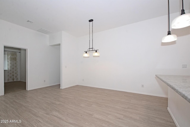 unfurnished dining area featuring light wood-style flooring and baseboards