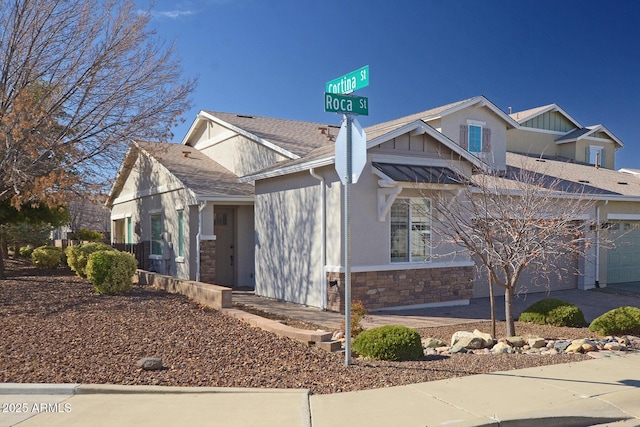 view of side of home featuring stone siding, roof with shingles, and driveway