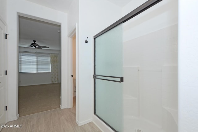 full bath featuring a ceiling fan, a stall shower, and wood finished floors