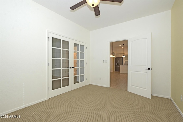 empty room with carpet floors, french doors, ceiling fan, and baseboards