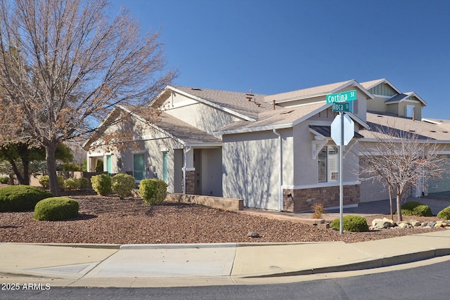 craftsman house featuring stone siding, a shingled roof, and stucco siding