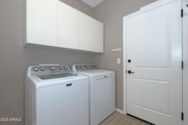 clothes washing area with light wood-type flooring, cabinet space, and washer and dryer