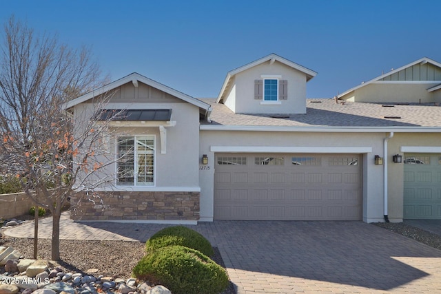 view of front of home featuring decorative driveway, stone siding, a shingled roof, and stucco siding