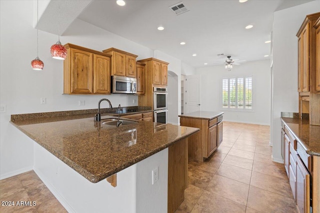 kitchen featuring a kitchen island, hanging light fixtures, ceiling fan, appliances with stainless steel finishes, and light tile floors