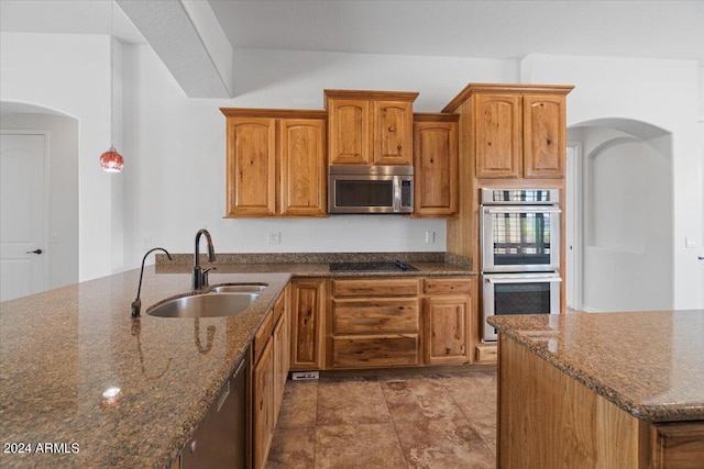 kitchen with stainless steel appliances, tile floors, dark stone counters, decorative light fixtures, and sink