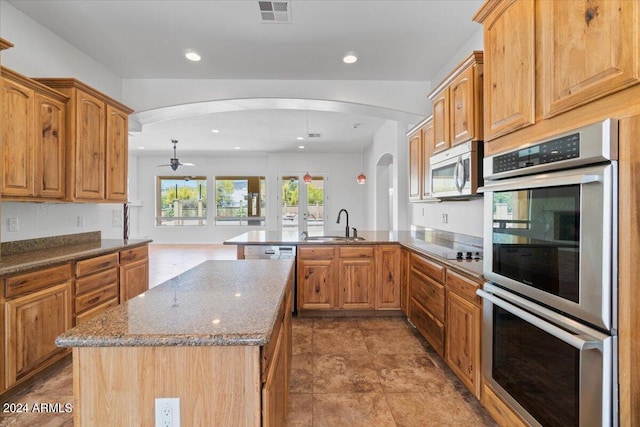 kitchen featuring light tile flooring, stainless steel appliances, ceiling fan, an island with sink, and sink