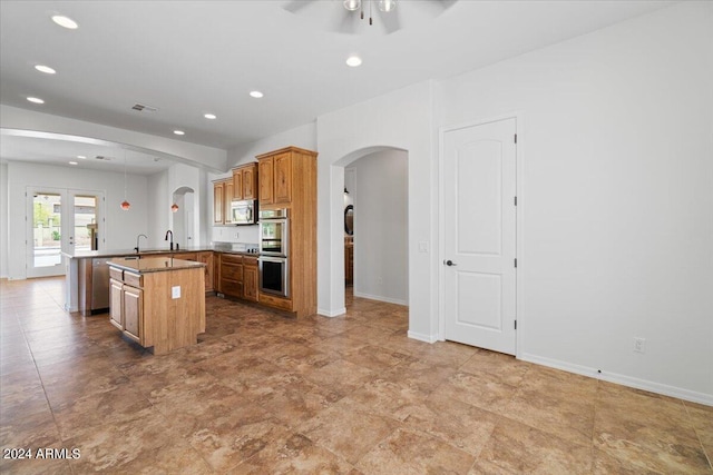 kitchen with a center island with sink, appliances with stainless steel finishes, kitchen peninsula, ceiling fan, and light tile floors