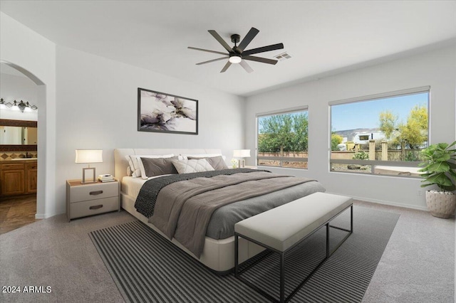 bedroom featuring carpet flooring, ensuite bathroom, and ceiling fan