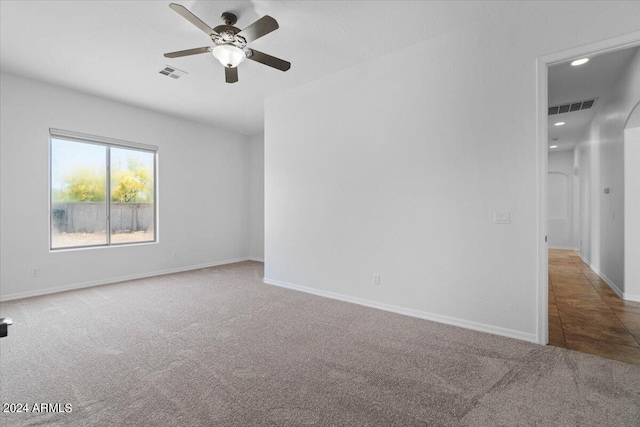 spare room featuring ceiling fan and dark carpet